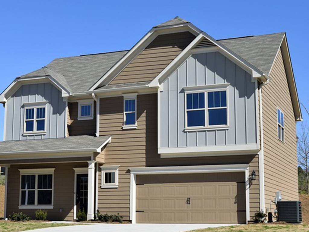 Nouvelle maison 2024 au allure brun pâle et un gris bleuté au bord d'une foret au loin.